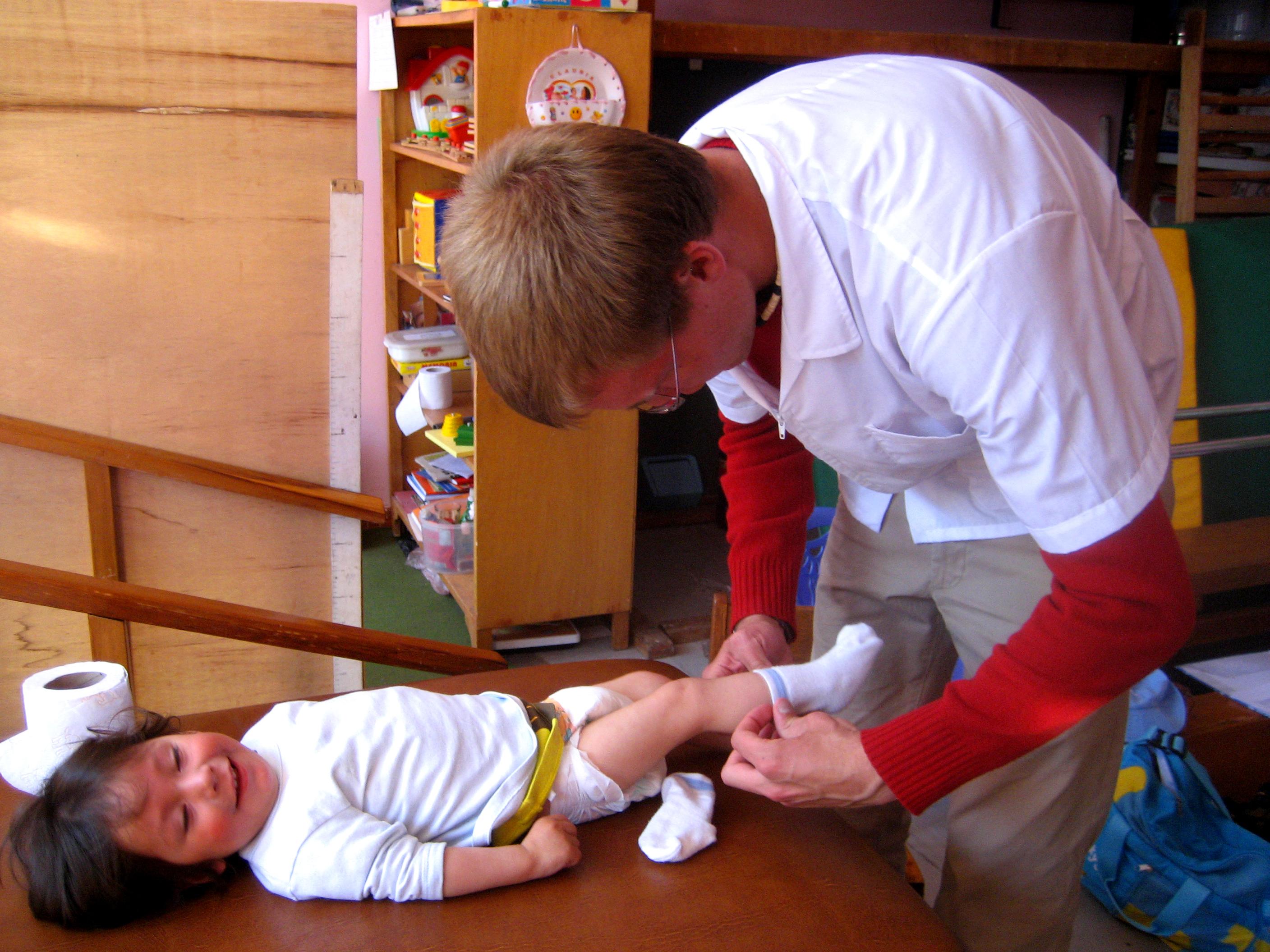A male Projects Abroad Intern putting a baby into new clothes as part of his midwifery internship in Peru. A male intern from Projects Abroad is pictured dressing a baby in new clothes as part of his midwifery internship in Peru.